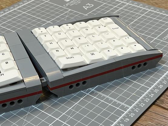 One side of a grey and red LEGO split keyboard with white low profile keycaps.