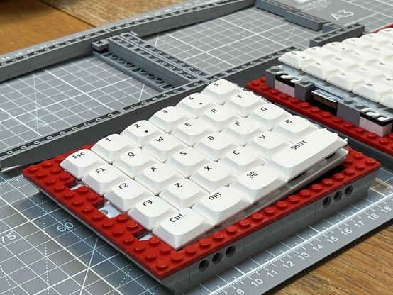 A LEGO split keyboard with the top layer removed showing the red stripe detail.