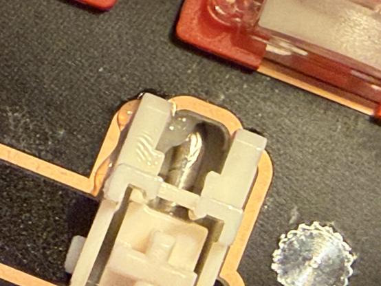 A closeup of one end of the spacebar stabiliser, showing lube squishing out onto the PCB edge.
