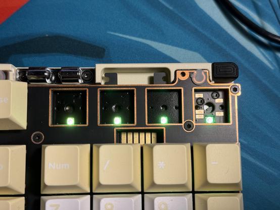 A keyboard PCB with four empty switch placements. The one on the far right has top facing copper pads for a rotary encoder with spring contacts.
