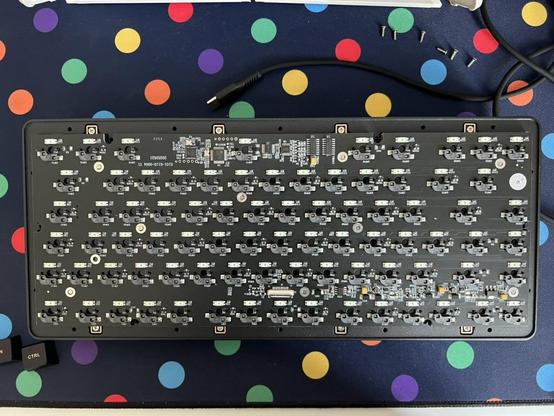 The top shell of a mechanical keyboard with the PCB and plate assembly screwed into place. Screws and wires are laid messily to one side.