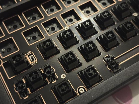 A mechanical keyboard with keycaps and many switches removed, revealing the hybrid mechanical and magnetic landings.