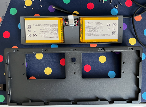 Disassembled parts of a mechanical keyboard, revealing two separate LiPo battery packs and a hevty metal weight.