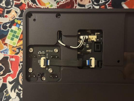 The back of a mechanical keyboard with the cover removed showing a JST connector for the battery, another for the volume rolled and a flat flex cable going to the four way nav PCB.
