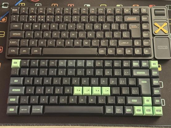 Two compact 75% keyboards next to each other, they are similarly sized but the upper one - the IQUNIX board - has extra controls on the right and a bezel (or flange?) around the keybed.