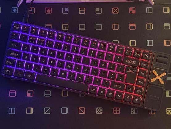 A top down view of a 75% ISO UK mechanical keyboard showing blue/pink/red gradient of light shining between the keycaps.