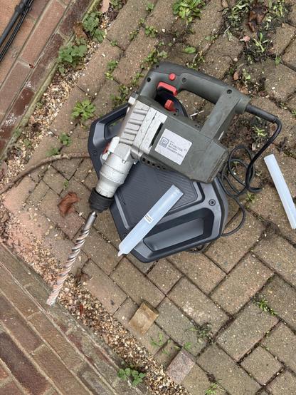 A huge, quite old SDS drill sat on top of a portable battery and plugged into its AC socket.