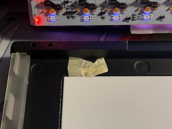 A creased scrap of masking tape holding some component or another into the inside of an aluminium keyboard bottom shell.