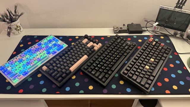 Four hefty aluminium mechanical keyboards arrayed on a dotty desk mat.