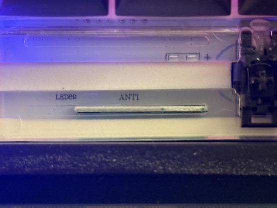 An edge on view of a green PCB fit upright into a white PCB. It’s a small PCB antenna for the keyboard’s Bluetooth and/or 2.4GHz wireless.