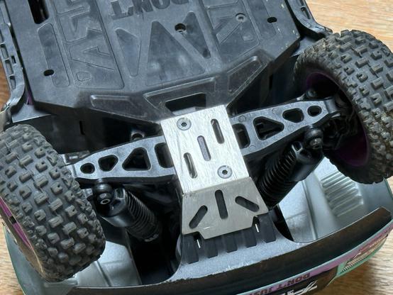 A metal skid plate on the underside front of an RC car. It’s already scuffed after just a day of driving.
