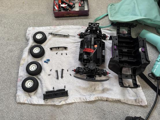 The body of an RC car sat between the parts of its disassembled top shell, all drying on a towel after being rinsed.