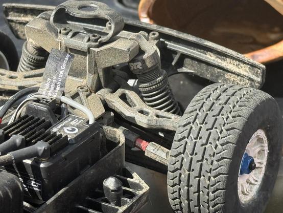 The front suspension of an RC car, caked in dust and dirt.
