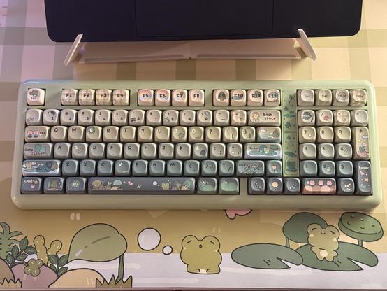 A KiiBOOM Phantom98 Lite mechanical keyboard in frog green with frog themed keycaps on a froggy themed desk mat.