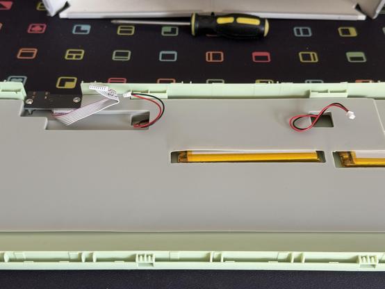 A heavy silicone padding layer in the bottom half of a frog green keyboard, various wires for the batteries and USB connector poke out.