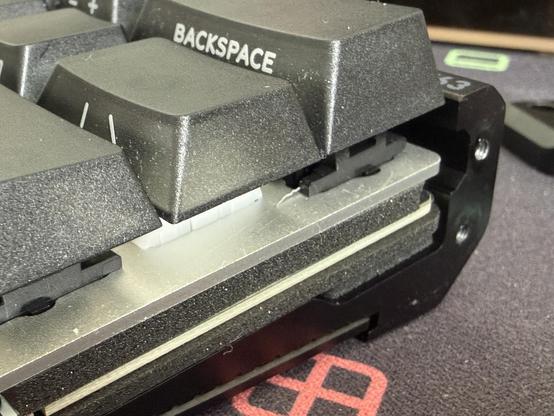A side on view of the plate and PCB slot into a metal keyboard base, they sandwich a layer of foam with additional foam underneath.