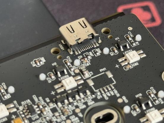 A closeup of the USB C port on a keyboard PCB, densely packed components are placed around it. There are holes either side, perhaps for a reinforcement part that was never used.
