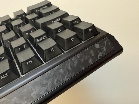 The front edge of the keyboard with a swirly patchwork of carbon fibre.