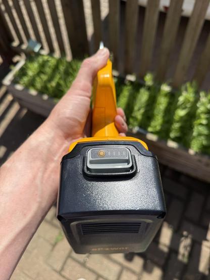 A bottom up view of huge battery attached to a set of electric pruning shears.