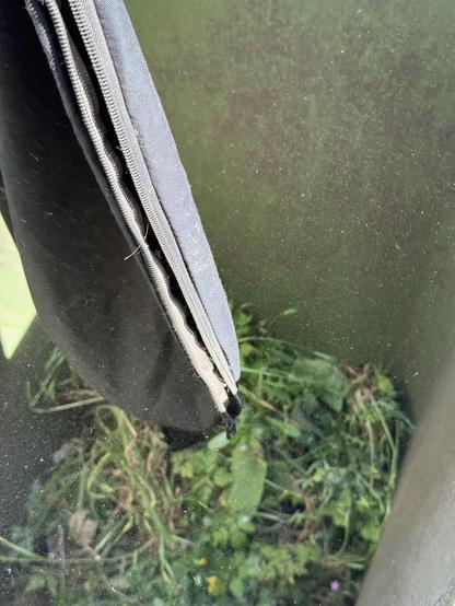 A fabric vacuum shredder bag held over an open garden waste bin. Specs catching the light suggest there is dust everywhere.