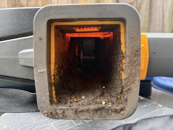 The vacuum outlet with the plastic clip still attached but the bag missing, the whole inside is absolutely caked in mud.