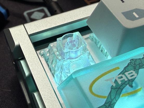 A closeup of a single transparent keyboard switch, adjacent a couple with caps on.