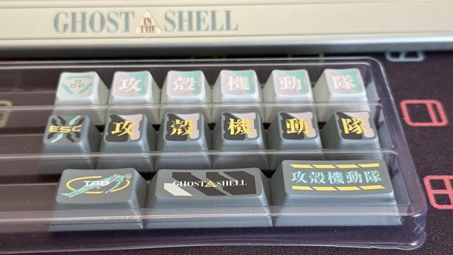 A set of opaque keycaps to replace some of the translucent ones and some mystery additional caps to replace part of the number row with the ghost in the shell (or riot police as it were) kanji.