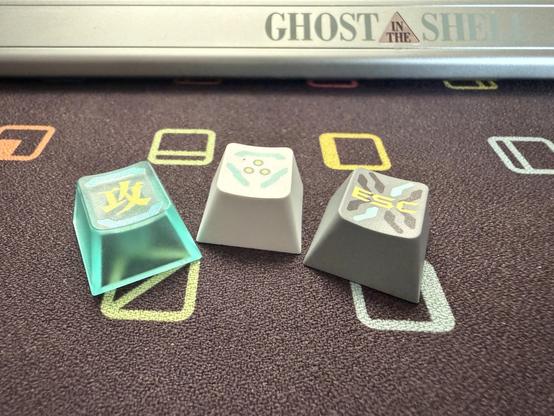 Three variations of keycap. Translucent teal, light grey and mid grey. The teal wins by a country mile.